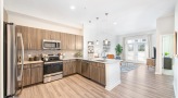 Spacious and well lit kitchen with stainless steel appliances and dark accents 