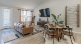 Spacious and well lit living room with wood floors and a large window
