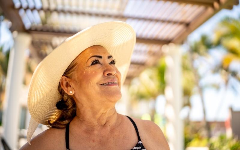 A resident standing and smiling outdoors by the swimming pool at Overture Dr. Phillips apartments in Orlando, FL.