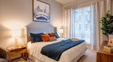 Model bedroom at Overture Yorktown 55 and older apartments in Lombard, IL, featuring carpeted flooring.