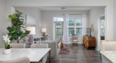 Spacious and well lit living room with wood floors and a large window
