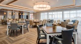 Resident lounge and dining hall at Overture Yorktown 55 and older apartments in Lombard, IL, featuring wood grain flooring.