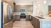 Spacious and well lit kitchen with stainless steel appliances and dark accents 