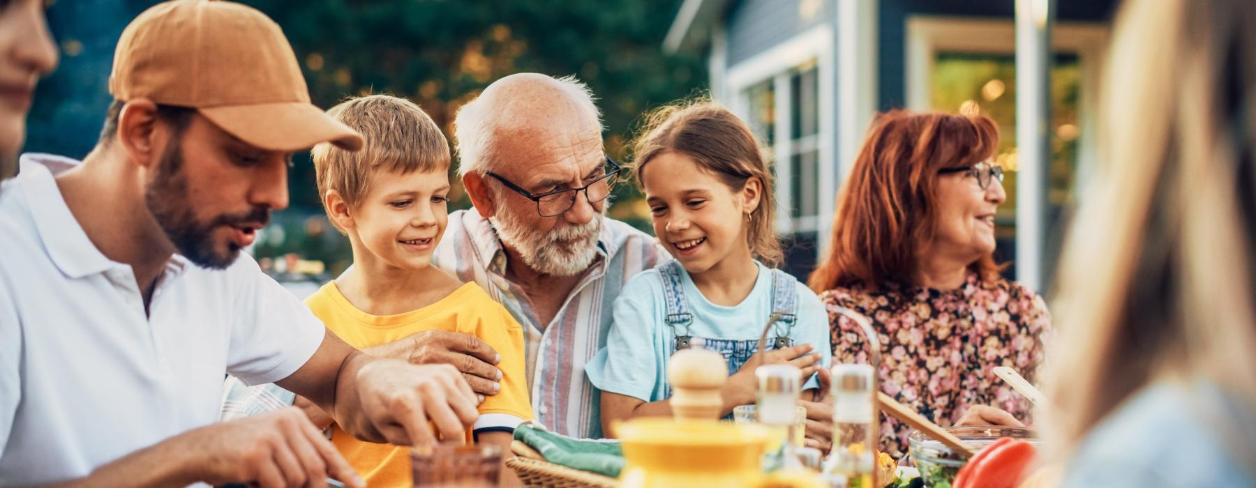 A family at a barbeque near Overture San Marcos over 55 apartments in San Marcos, CA, featuring smiling children.