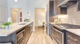 Model kitchen at Overture Yorktown 55 and older apartments in Lombard, IL, featuring wood grain floor paneling.