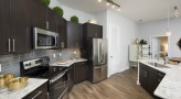 Spacious and well lit kitchen with stainless steel appliances and dark accents 