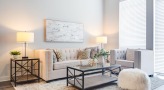 Spacious and well lit living room with wood floors and a large window