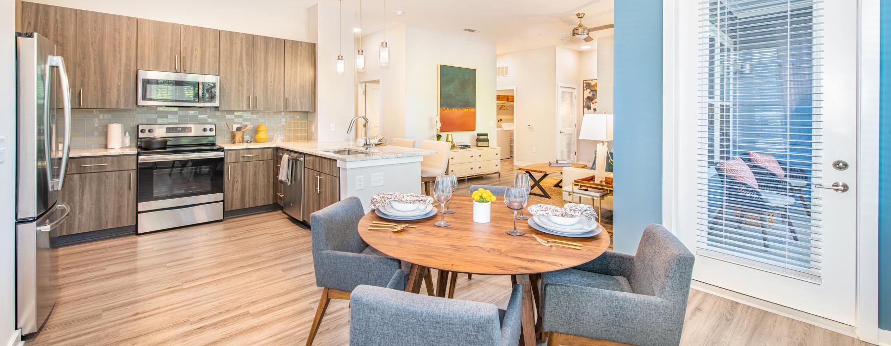 Model living room and kitchen at Overture Centennial senior living apartments in Raleigh, NC, featuring wood grain flooring.