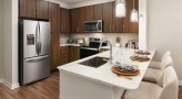 Spacious and well lit kitchen with stainless steel appliances and dark accents 