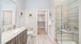 Large well lit bathroom with wood floors and walk in shower 