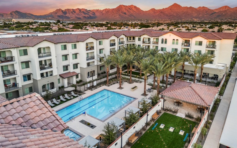 Aerial view of the Overture North Scottsdale senior community in Arizona, featuring lounge chairs and palm trees. 