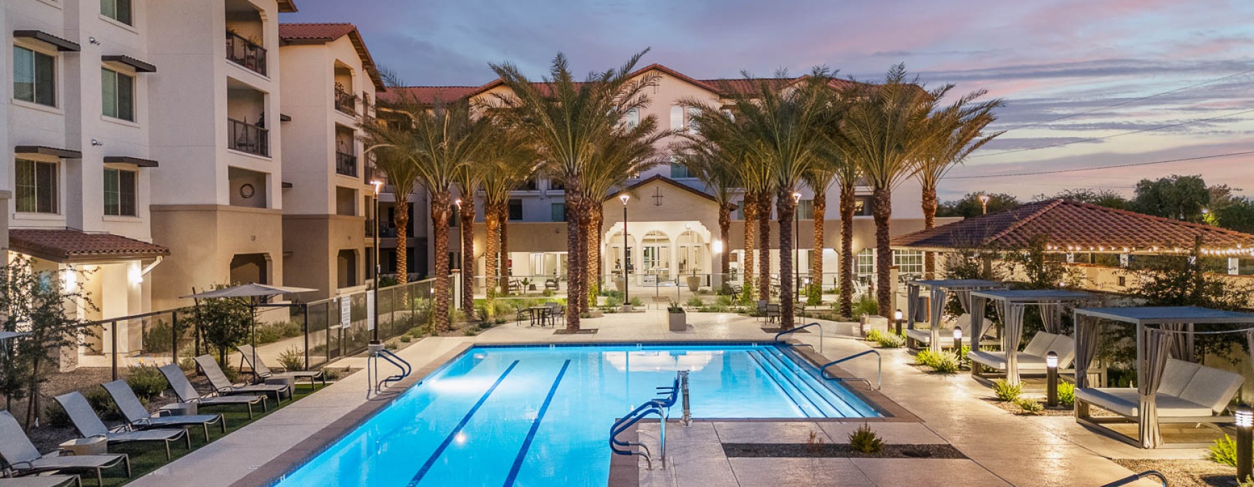 The pool area at Overture North Scottsdale senior community in Arizona, featuring lounge chairs and umbrellas. 