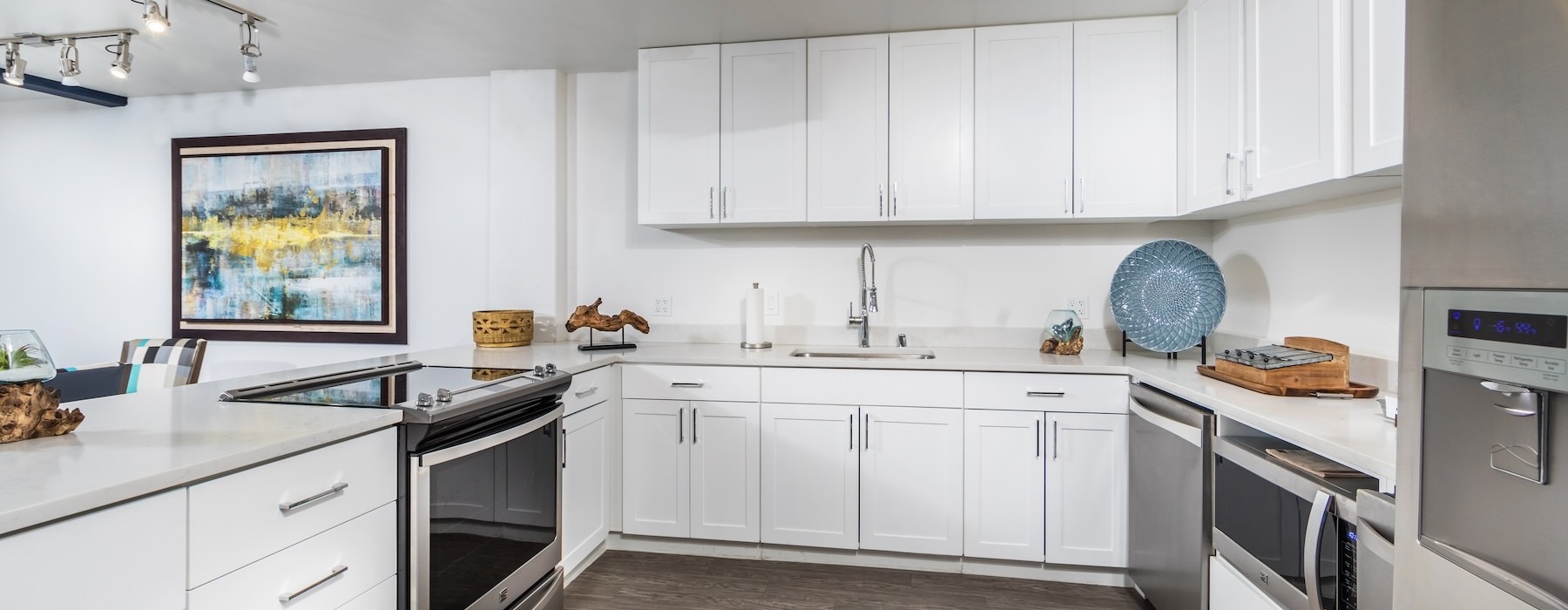 Model kitchen at Overture San Marcos over 55 apartments in San Marcos, CA, featuring white cabinetry and a kitchen island.
