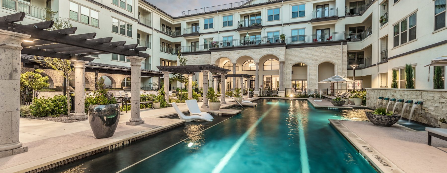 Outdoor swimming pool at Overture Stone Oak apartments in San Antonio, TX, with a view of the surrounding modern facade.