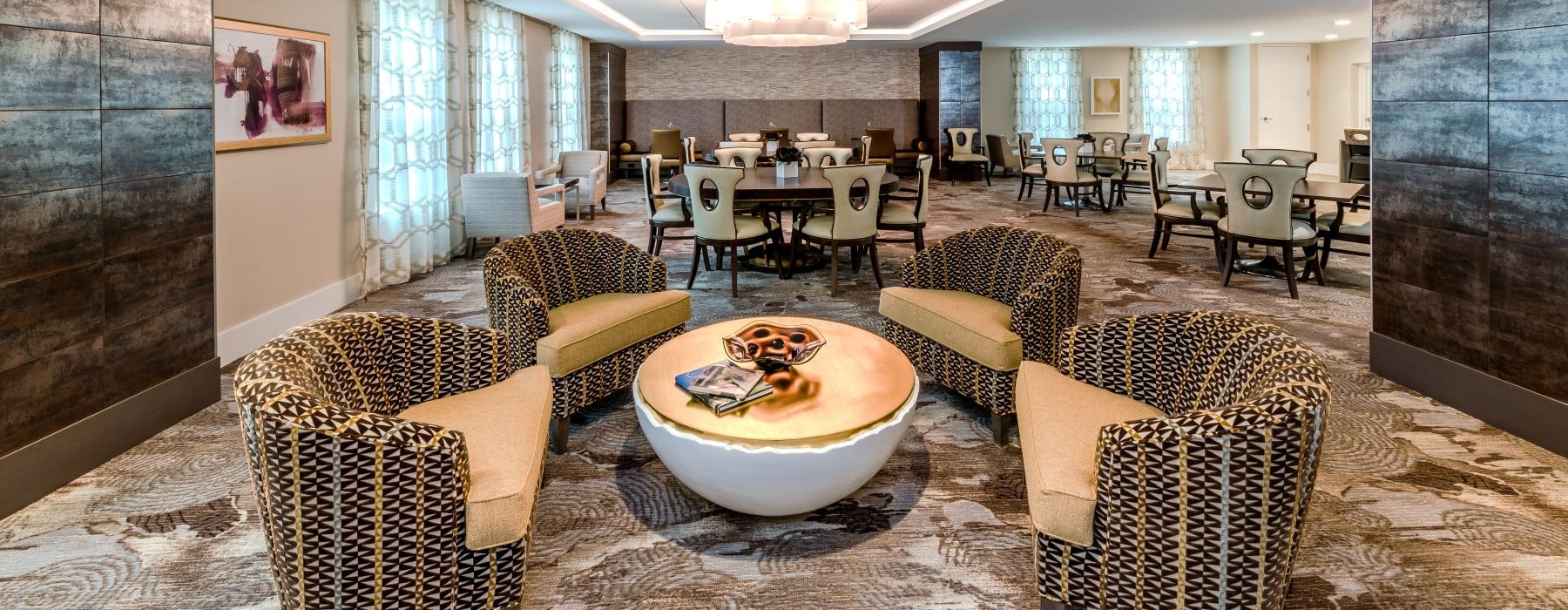 Resident lounge at Overture Fair Ridge senior living apartments in Fairfax, VA, featuring carpeted flooring and couches.