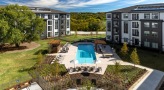 a building with a pool and trees in the front