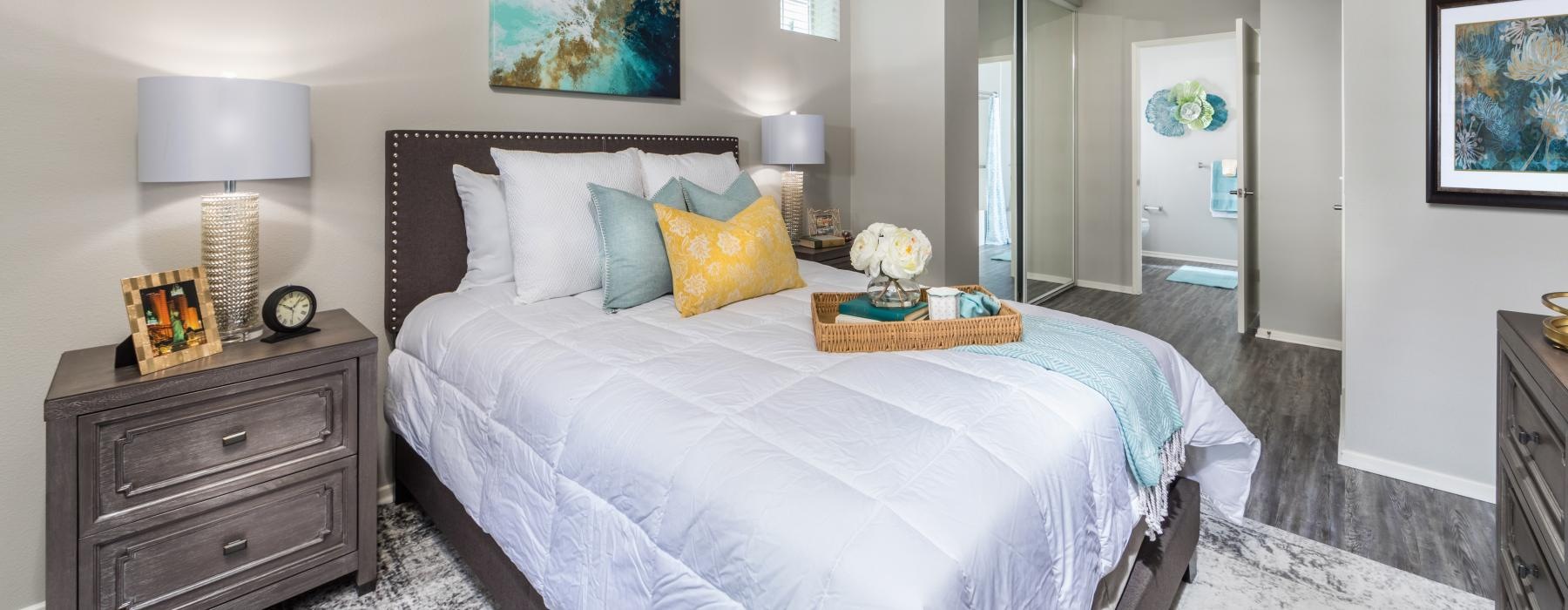 Model bedroom at Overture Riverwalk senior living apartments in Riverside, CA, featuring wood grain flooring. 