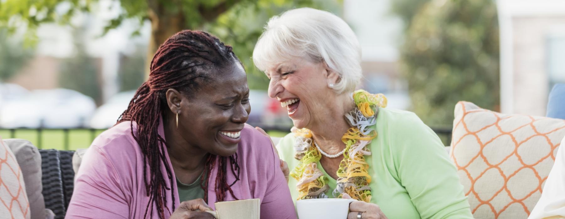 Two residents sitting outside and drinking tea at Overture North Scottsdale senior community in Arizona. 