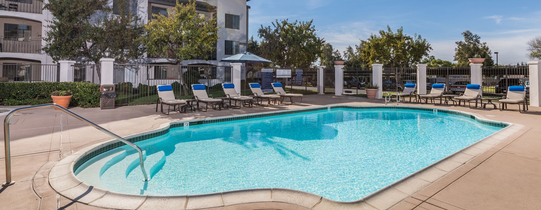 Pool area at Overture San Marcos over 55 apartments in San Marcos, CA, featuring lounge chairs and umbrellas.