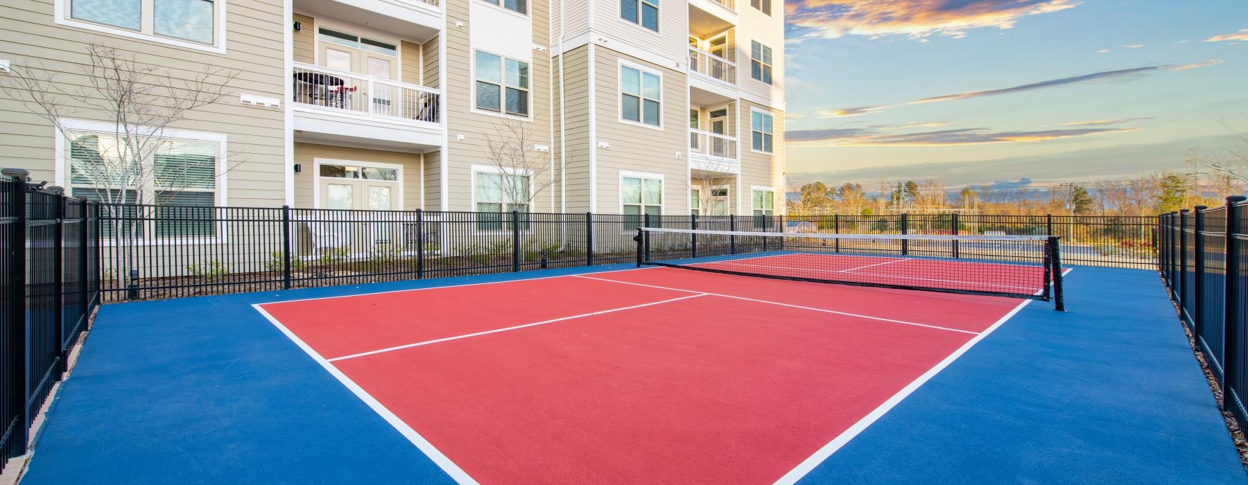 The tennis court at Overture Greenville senior living apartments in Greenville, featuring a view of the apartment exteriors.