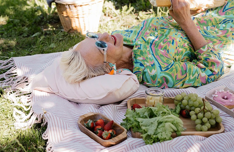 a woman lays on a blanket at an outdoor picnic
