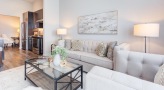 Model living room at Overture Yorktown 55 and older apartments in Lombard, IL, featuring white couches and rugs.