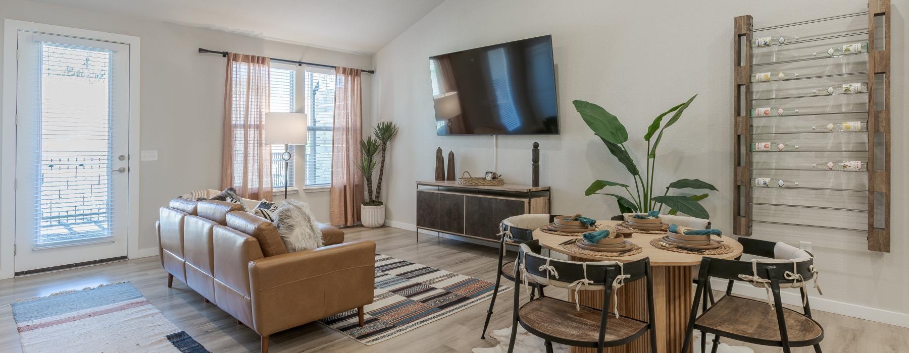 Model living room at Overture Andalucia senior living community in Albuquerque, NM, featuring wood grain flooring and a TV.