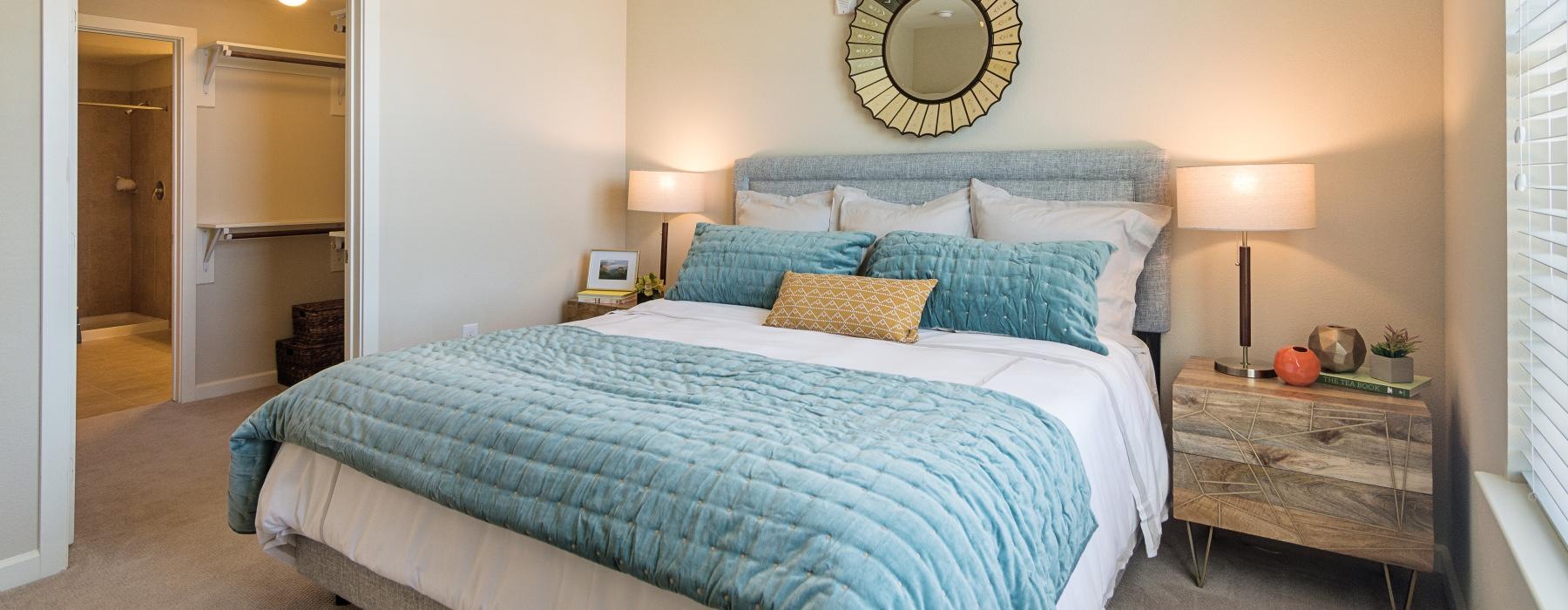 Model bedroom at Overture Frisco senior living apartments in Frisco, TX, featuring carpeted flooring and a walk-in closet.