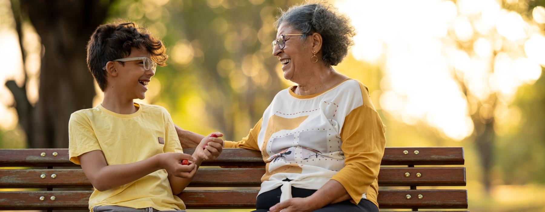 A resident sitting with a child on a bench at Overture Riverwalk senior living apartments in Riverside, CA.