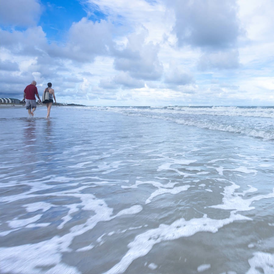 Charleston A couple walks along the beach as the tide comes in.