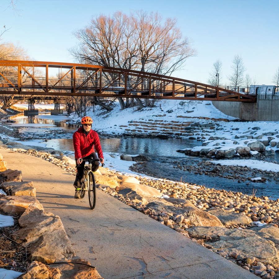 Denver Senior man riding a bicycle along a river in the winter in Colorado