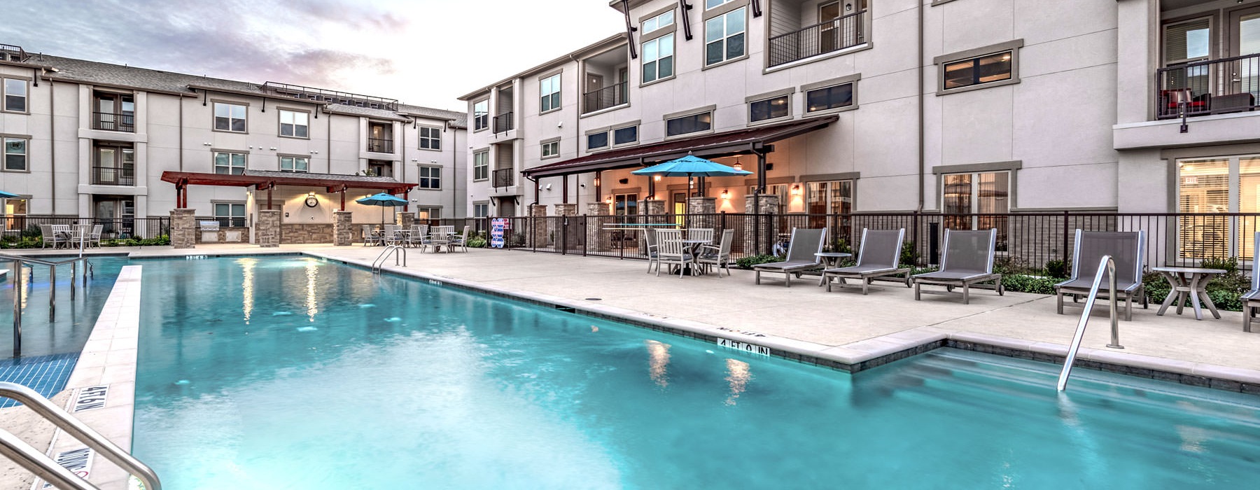 The pool lounge at Overture Frisco senior living apartments in Frisco, TX, featuring lounge chairs and umbrellas.