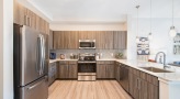 Spacious and well lit kitchen with stainless steel appliances and dark accents 