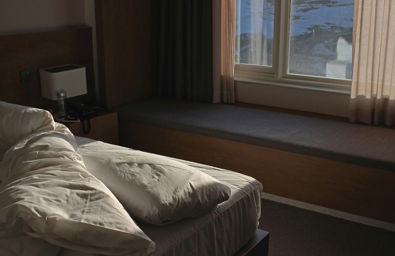 Model bedroom at Overture Fair Ridge senior living apartments in Fairfax, VA, featuring white bedspread.