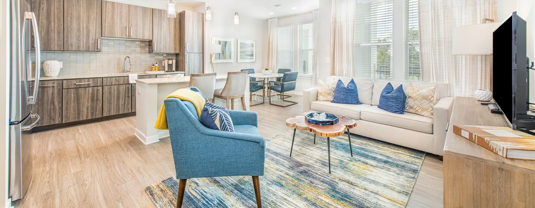 Model living room and kitchen at Overture Daniel Island senior living apartments in Charleston featuring wood grain flooring.