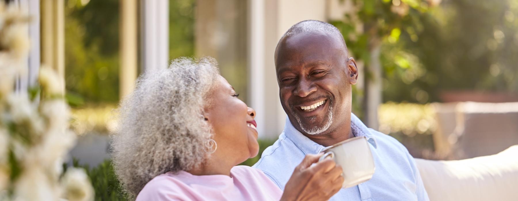 Two resident smiling and sitting outside at Overture San Marcos over 55 apartments in San Marcos, CA featuring warm sunlight.