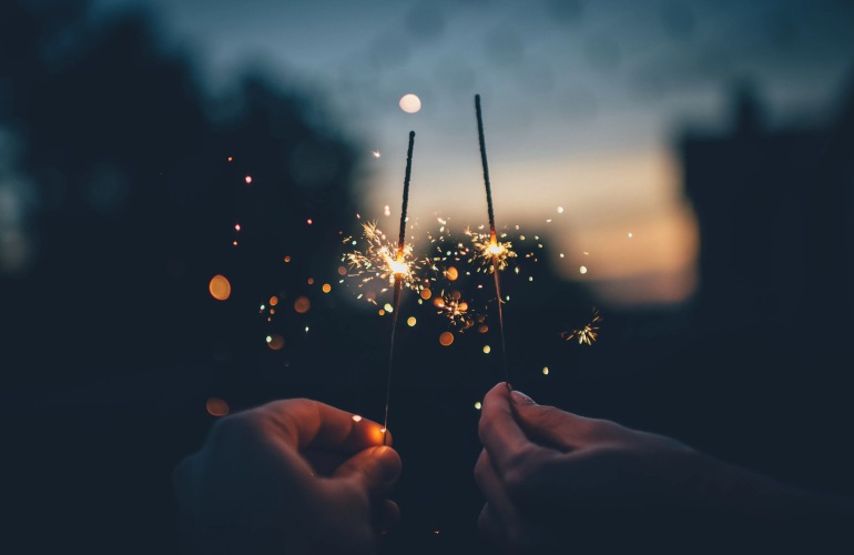 Close up of two hands holding sparklers