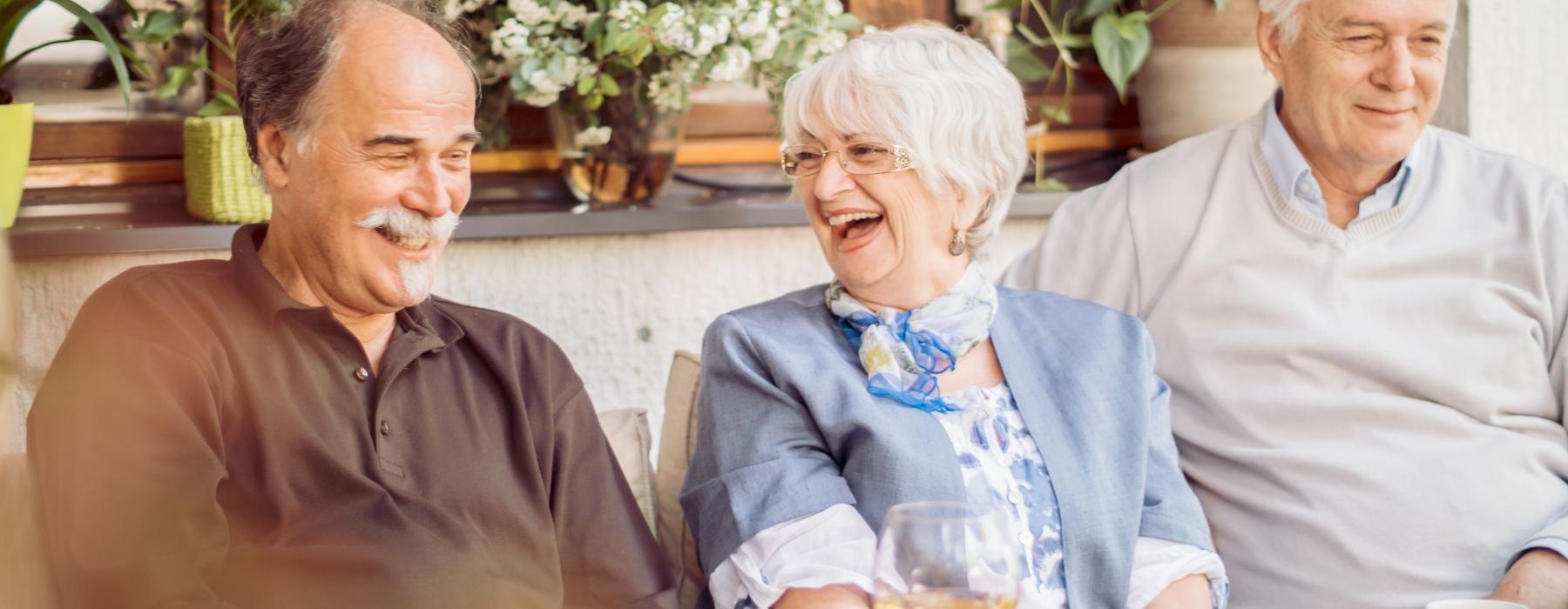Residents sitting outside and laughing at Overture West Ashley senior living apartments in Charleston, SC.