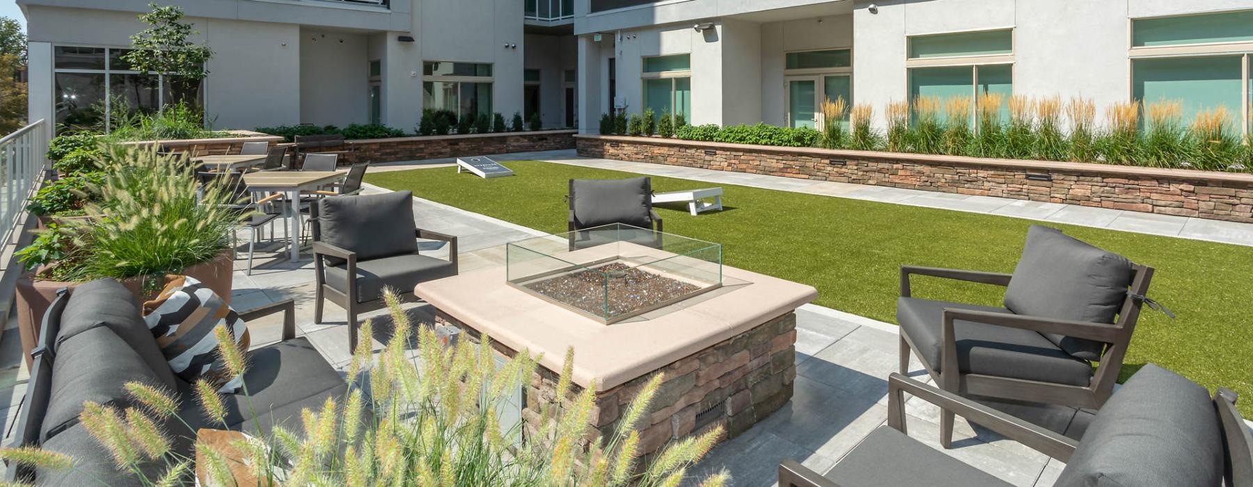 The outdoor lounge at Overture 9th + CO senior apartments in Denver, CO, featuring a firepit and lounge chairs.