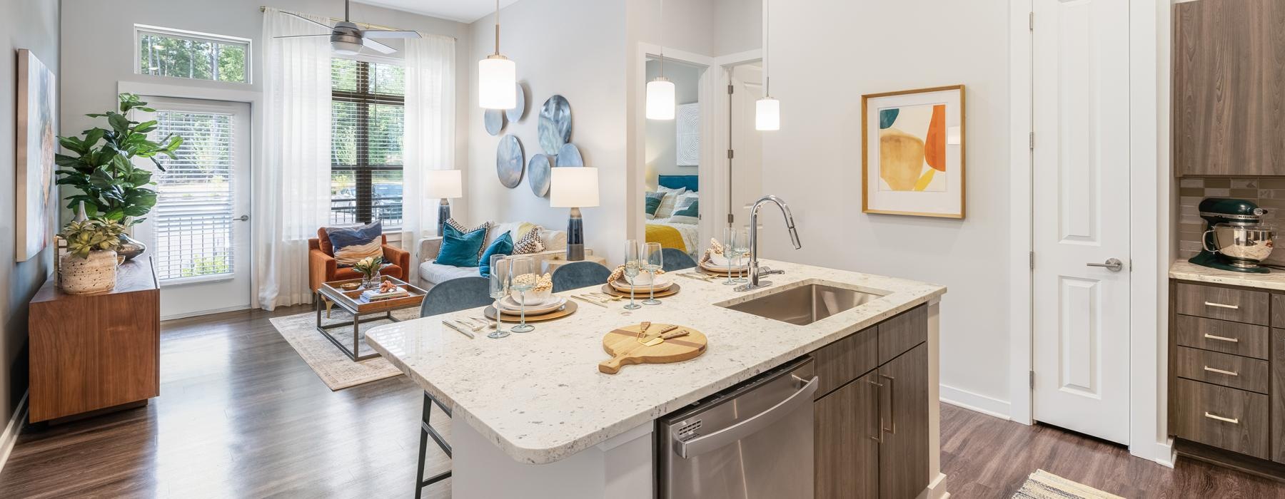 Model kitchen and living room at Overture Cary senior living apartments in Cary, NC, featuring a kitchen island.