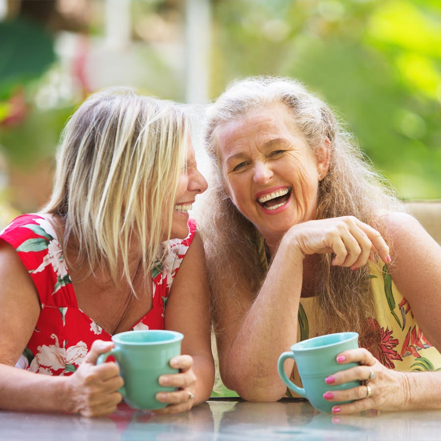 Orlando Two senior women enjoying coffee and laughter on a outdoor patio in Florida.
