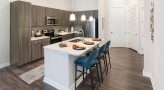 Spacious and well lit kitchen with stainless steel appliances and dark accents 