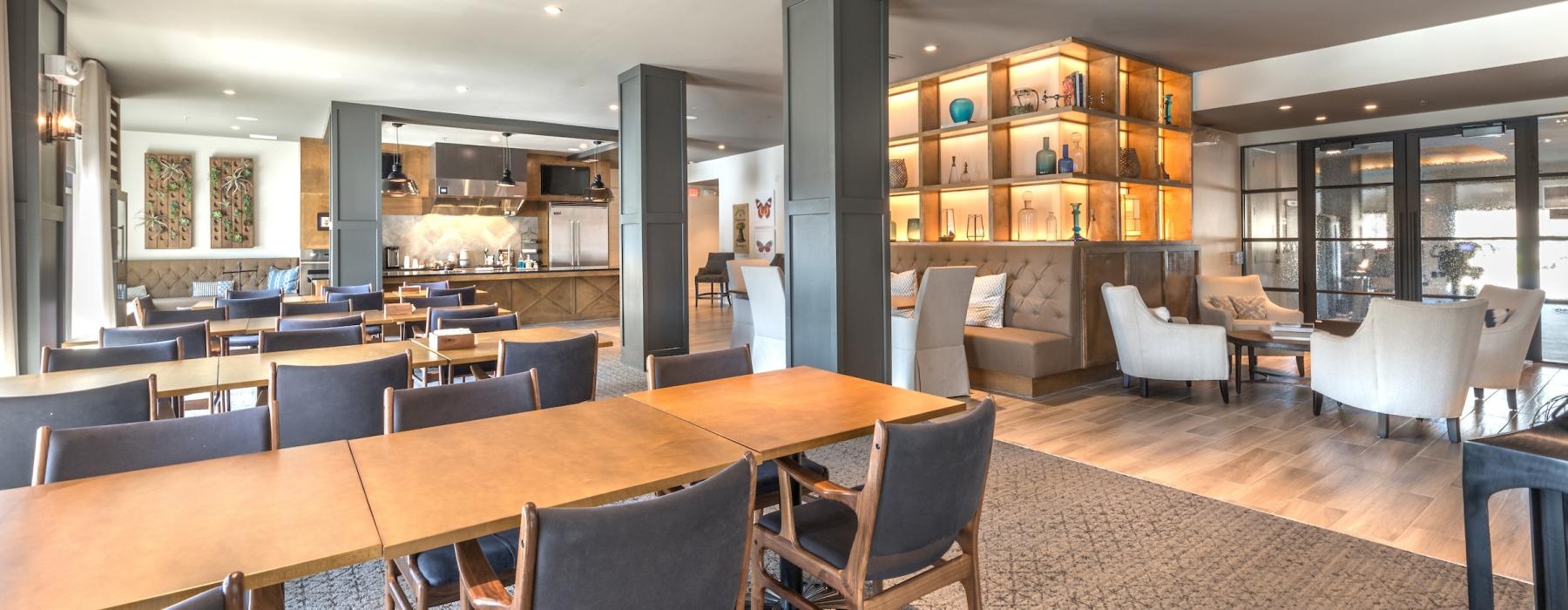 Resident lounge at Overture Highlands senior living apartments in Arlington, TX, featuring wooden tables with chairs.