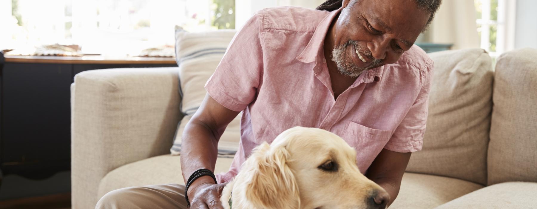 a man sitting on a couch petting a dog