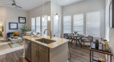 Spacious and well lit kitchen with stainless steel appliances and dark accents 