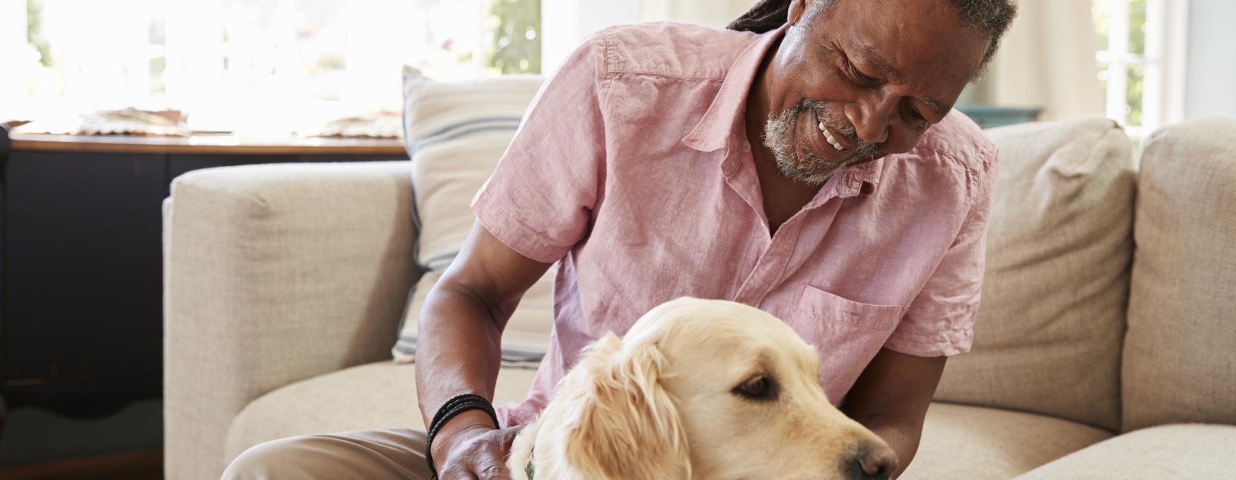A resident petting a dog at Overture North Scottsdale senior community in Arizona, featuring a beige couch. 