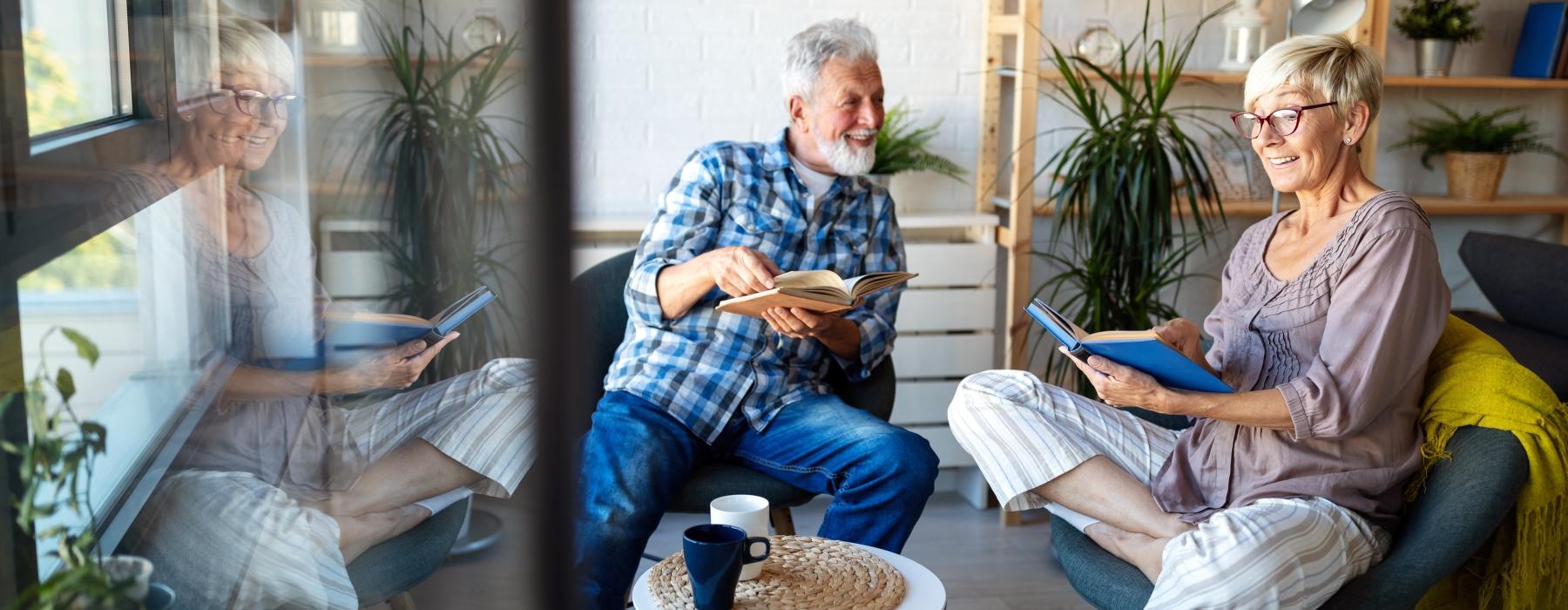 Two people laughing together and reading books in a modern living room at Overture Crabtree in Raleigh, NC.