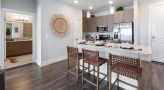 Spacious and well lit kitchen with stainless steel appliances and dark accents 