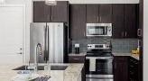 Spacious and well lit kitchen with stainless steel appliances and dark accents 