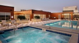 The pool area at Overture Yorktown 55 and older apartments in Lombard, IL, featuring lounge chairs and string lights.